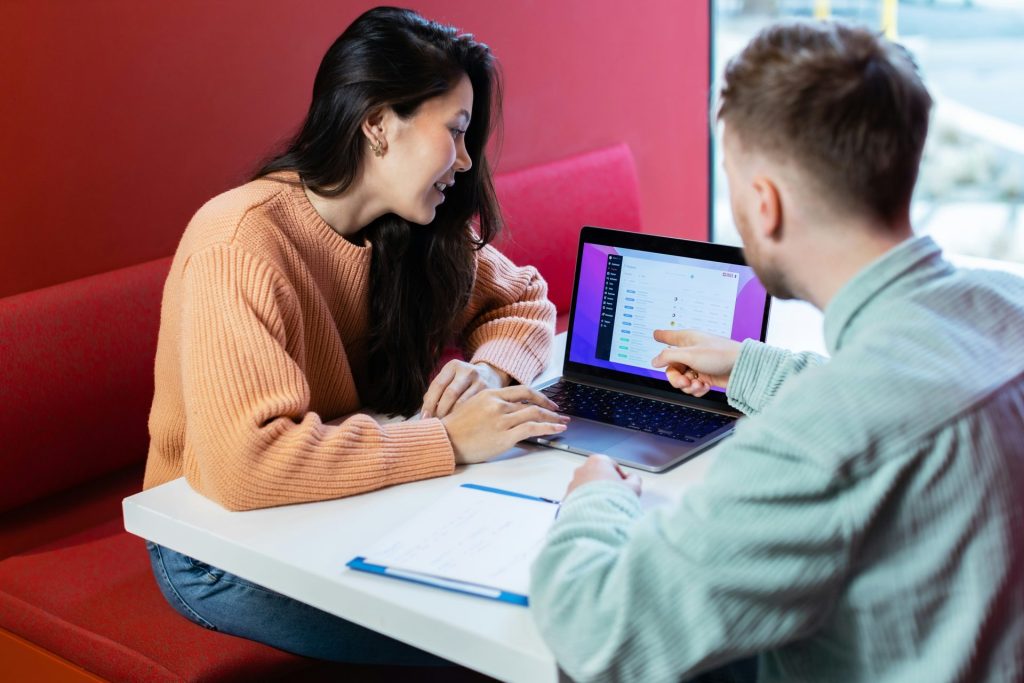 a man and a woman sitting at a table with a laptop